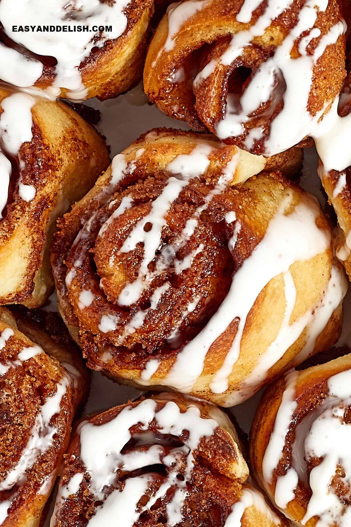 Close up cinnamon rolls drizzled with icing.