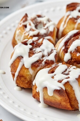 air fryer cinnamon rolls topped with cream cheese frosting on a side plate