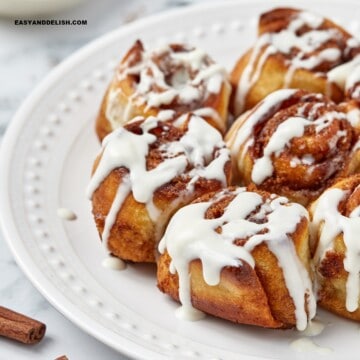 air fryer cinnamon rolls topped with cream cheese frosting on a side plate