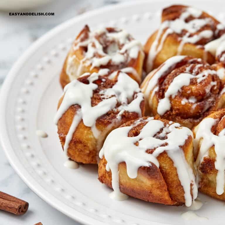 air fryer cinnamon rolls topped with cream cheese frosting on a side plate