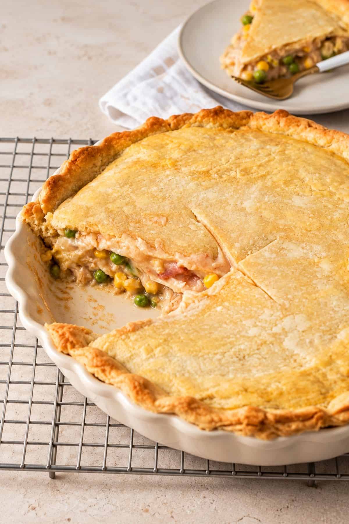 Golden chicken pot pie with a slice removed, exposing the creamy filling inside a patterned blue pie dish.