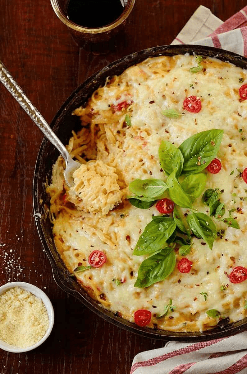 a skillet with chicken pasta bake  garnished with toatoes and with cheese on the side