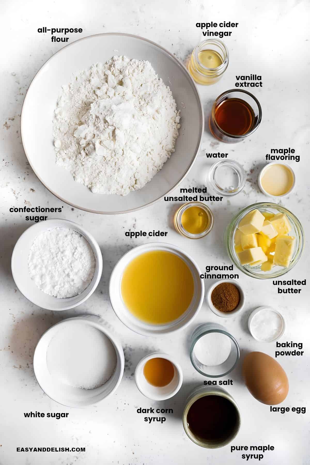 Ingredients for apple cider donuts and maple glaze arranged on a white surface.