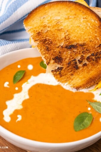 close up of grilled cheese sandwich dipped in a bowl of keto tomato soup