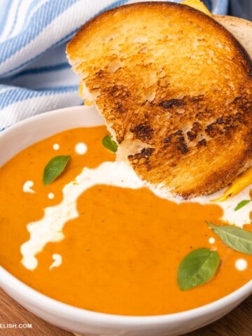 close up of grilled cheese sandwich dipped in a bowl of keto tomato soup