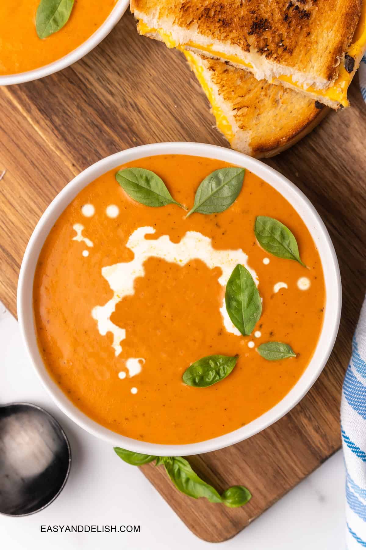 a large bowl of tomato soup garnished on top with basil and cream