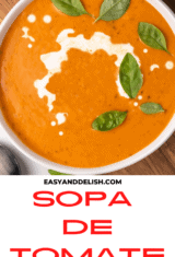 close up de sopa de tomate guarnecida no topo com manjericao e creme de leite