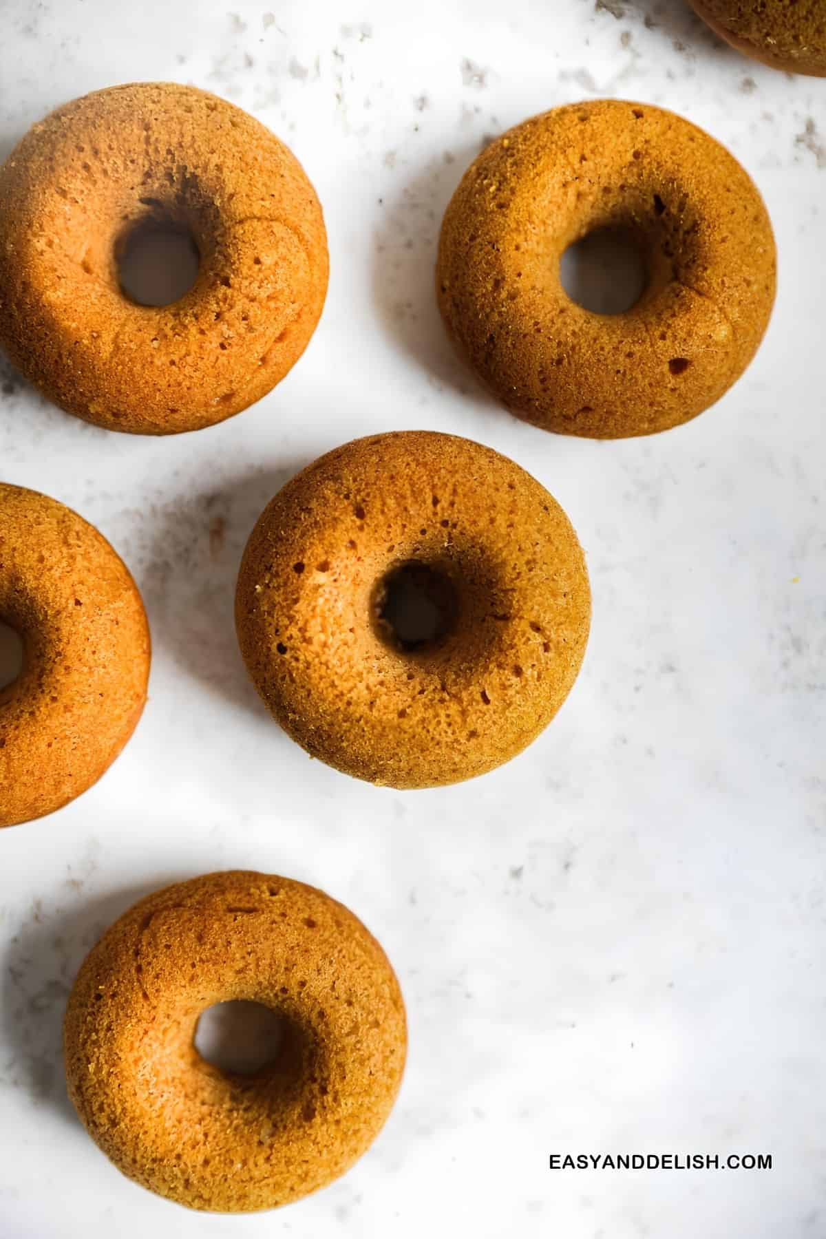 Unglazed mini baked donuts cooling before the maple glaze is added.