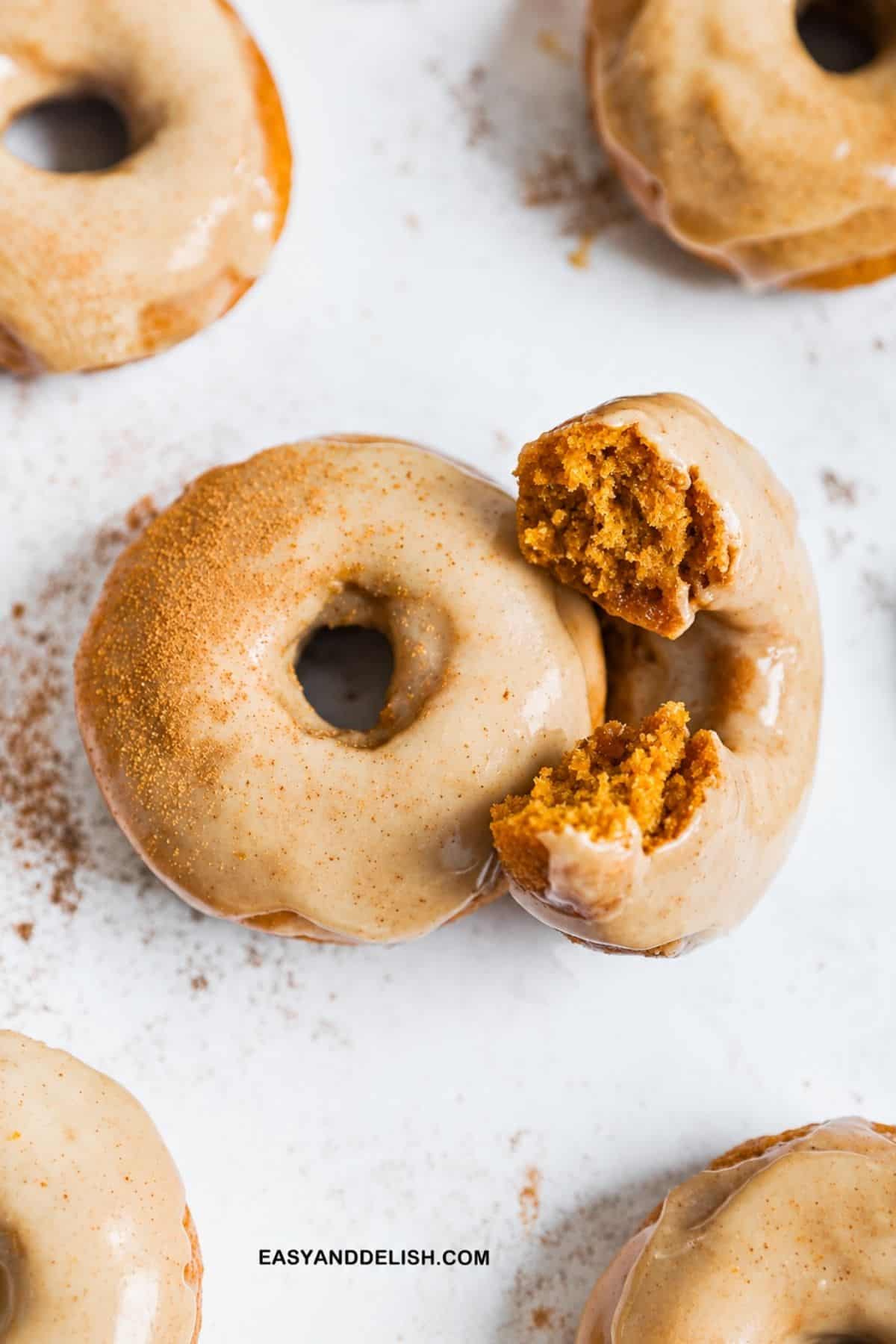 Glazed mini donuts with broken pieces showing the soft pumpkin crumb.
