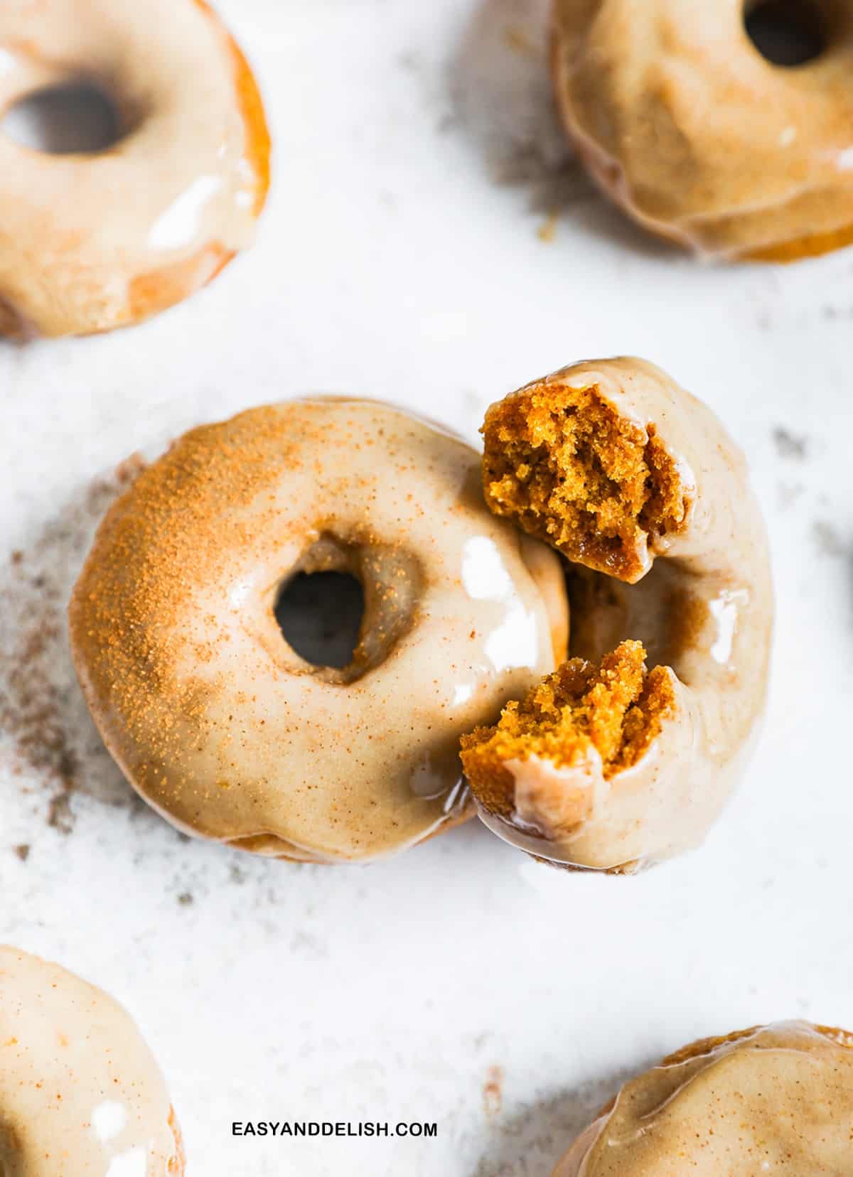 bitten and whole glazed pupkin donuts on a table
