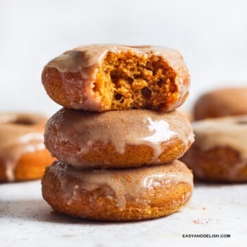 a pile of three glazed baked pumpkin donuts on a table