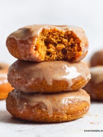 a pile of three glazed baked pumpkin donuts on a table