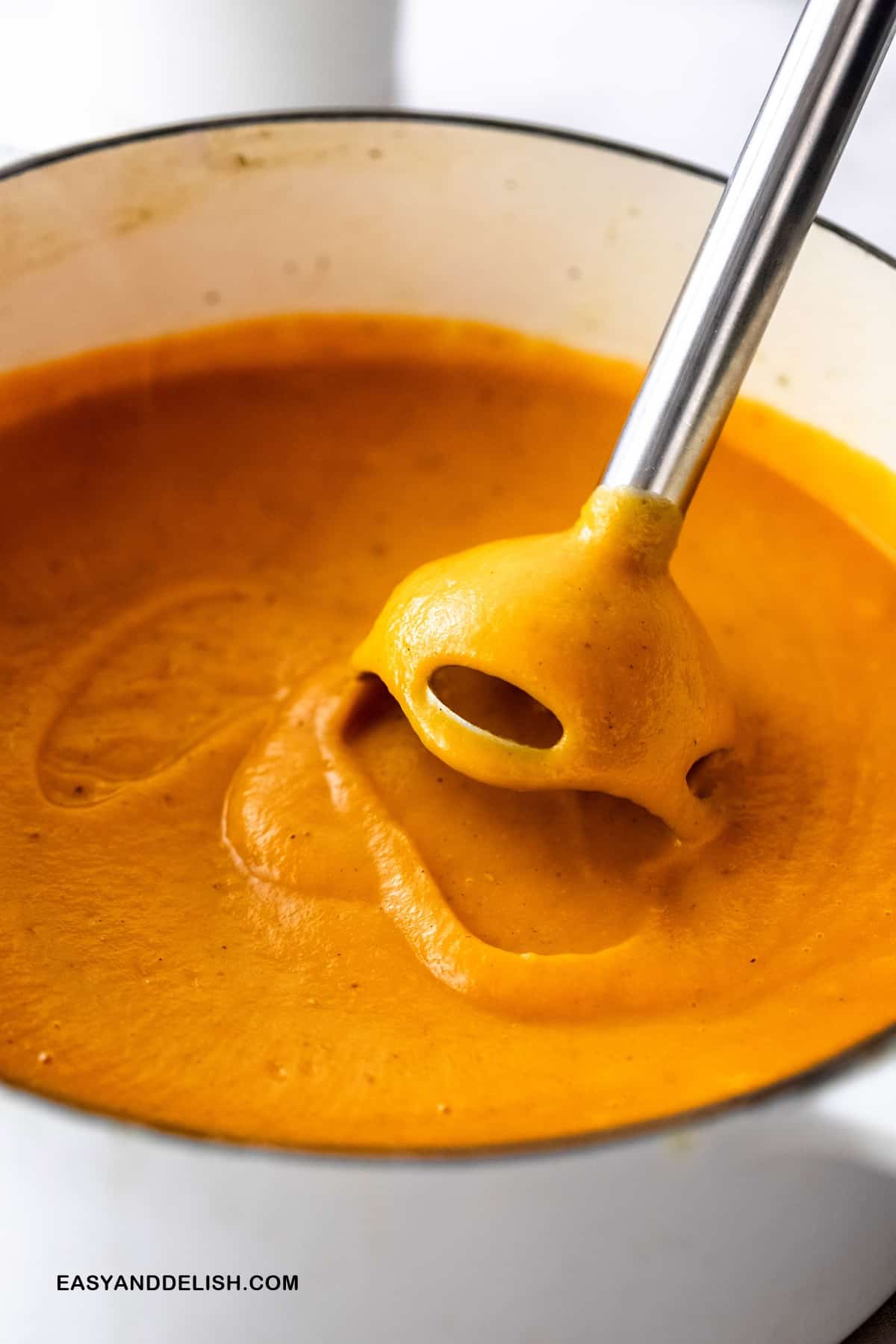 immersion blender blending the cooked veggies in a pot