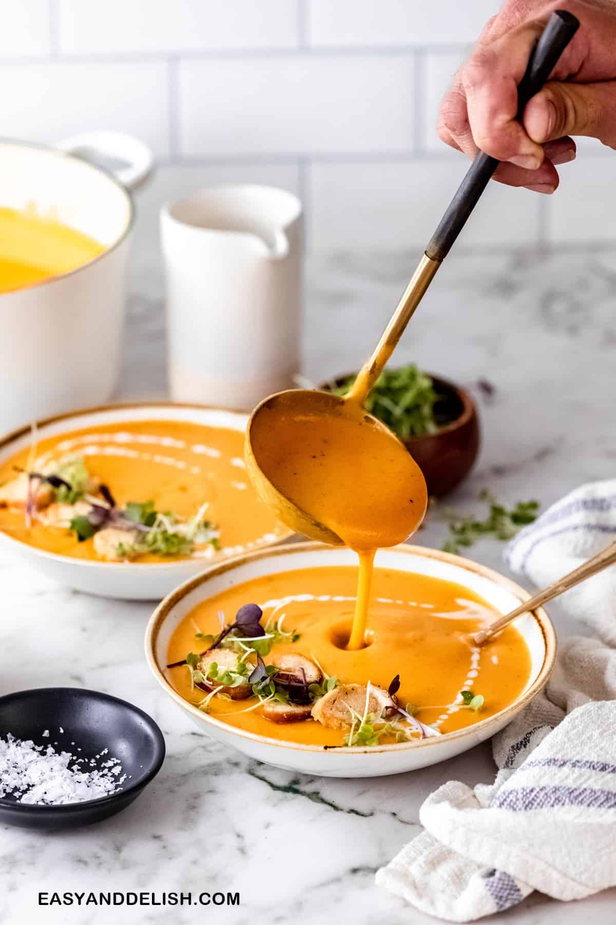 a ladle pouring soup in a bowl 