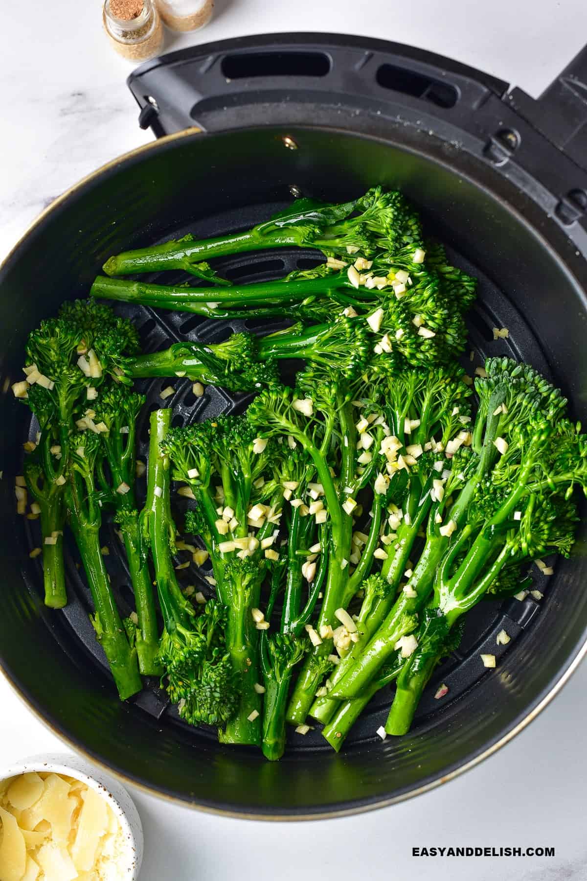 broccolini in air fryer topped with minced garlic