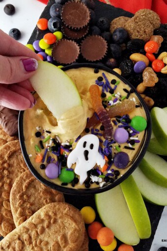 an apple slice dipped in a bowl of pumpkin dip