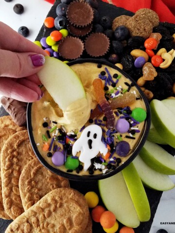 an apple slice dipped in a bowl of pumpkin dip