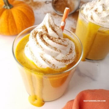 close up of a glass of pumpkin spice protein shake with a straw in it.