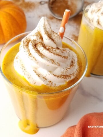 close up of a glass of pumpkin spice protein shake with a straw in it.