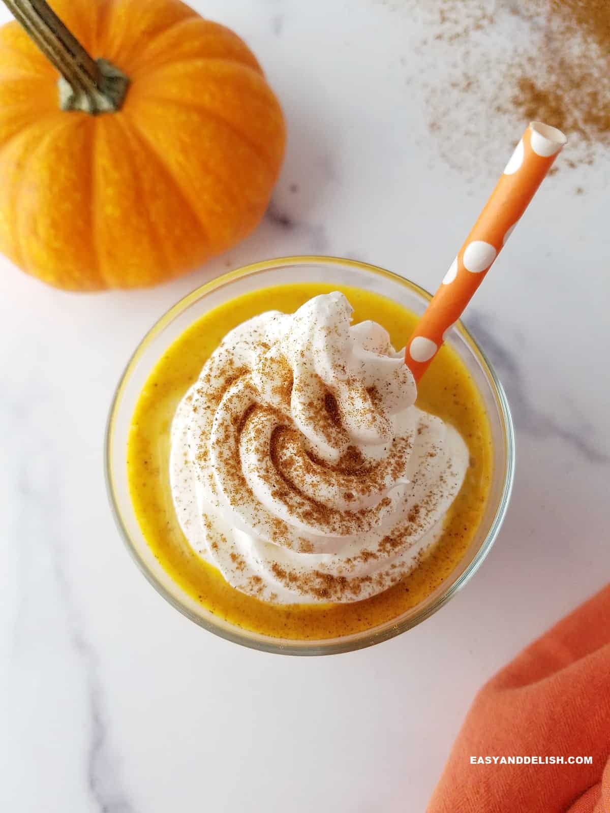 a glass of pumpkin protein shake topped with sugar-free whipped cream and pumpkin spice
