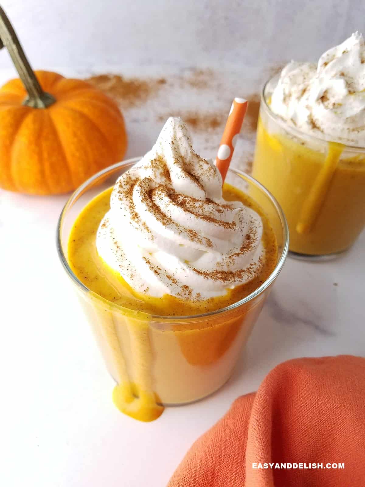 two glasses of a healthy drink for breakfast on atable with a small pumpkin on the side.