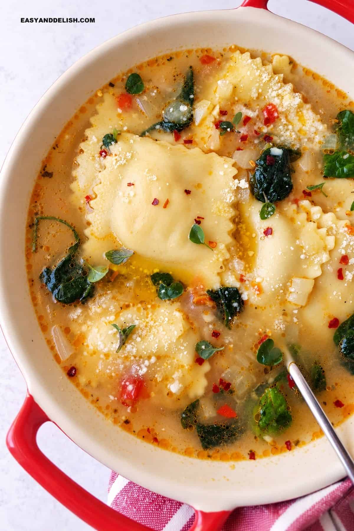 Cheese ravioli with spinach, Parmesan, herbs, and broth in a serving bowl.