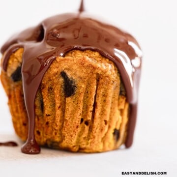 close up of a pumpkin chocolate chip muffin drizzled with melted chocolate.
