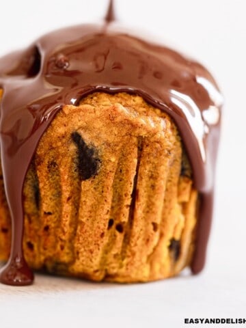 close up of a pumpkin chocolate chip muffin drizzled with melted chocolate.