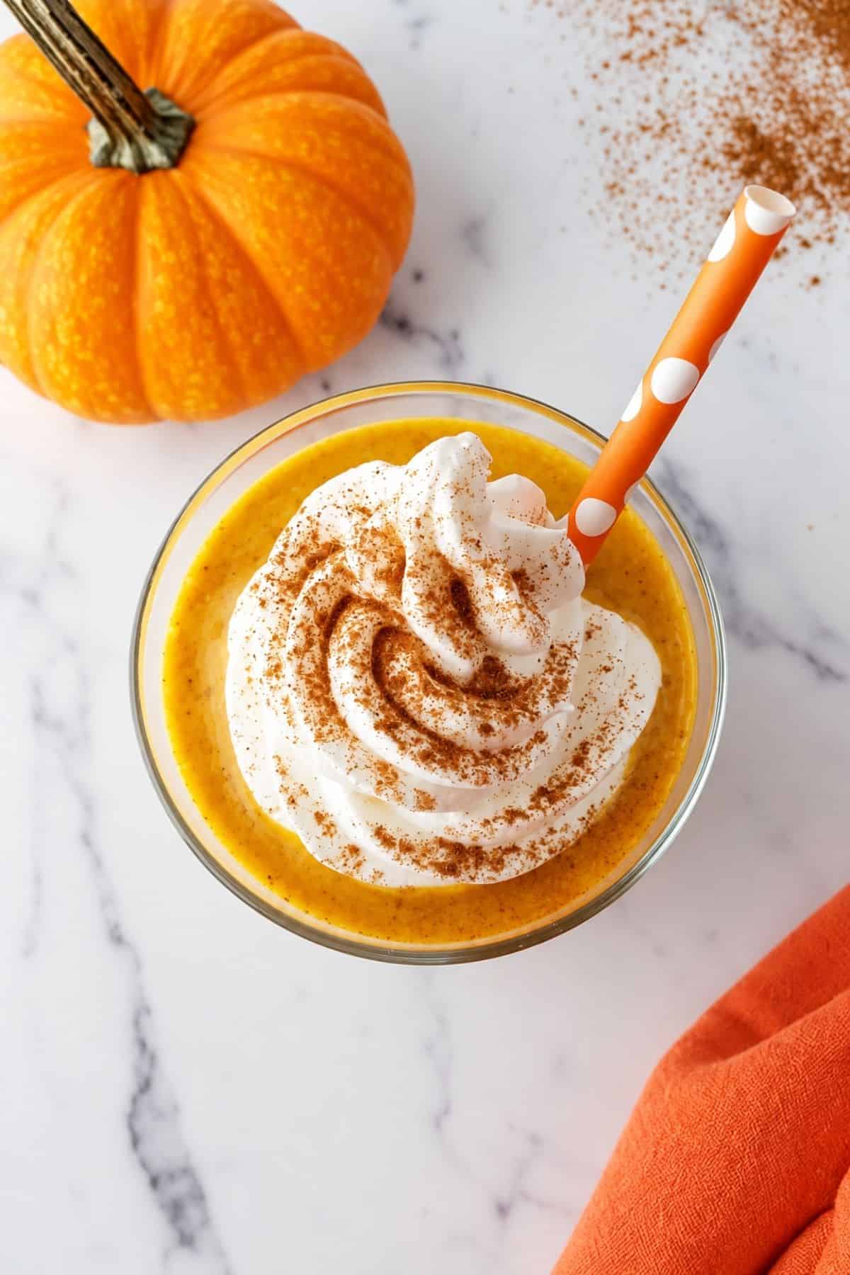 Overhead view of a pumpkin shake topped with whipped cream and pumpkin pie spice.