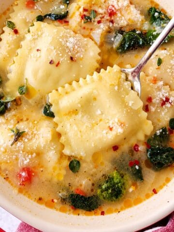 Filled pasta topped with Parmesan in a light broth with leafy greens and herbs.