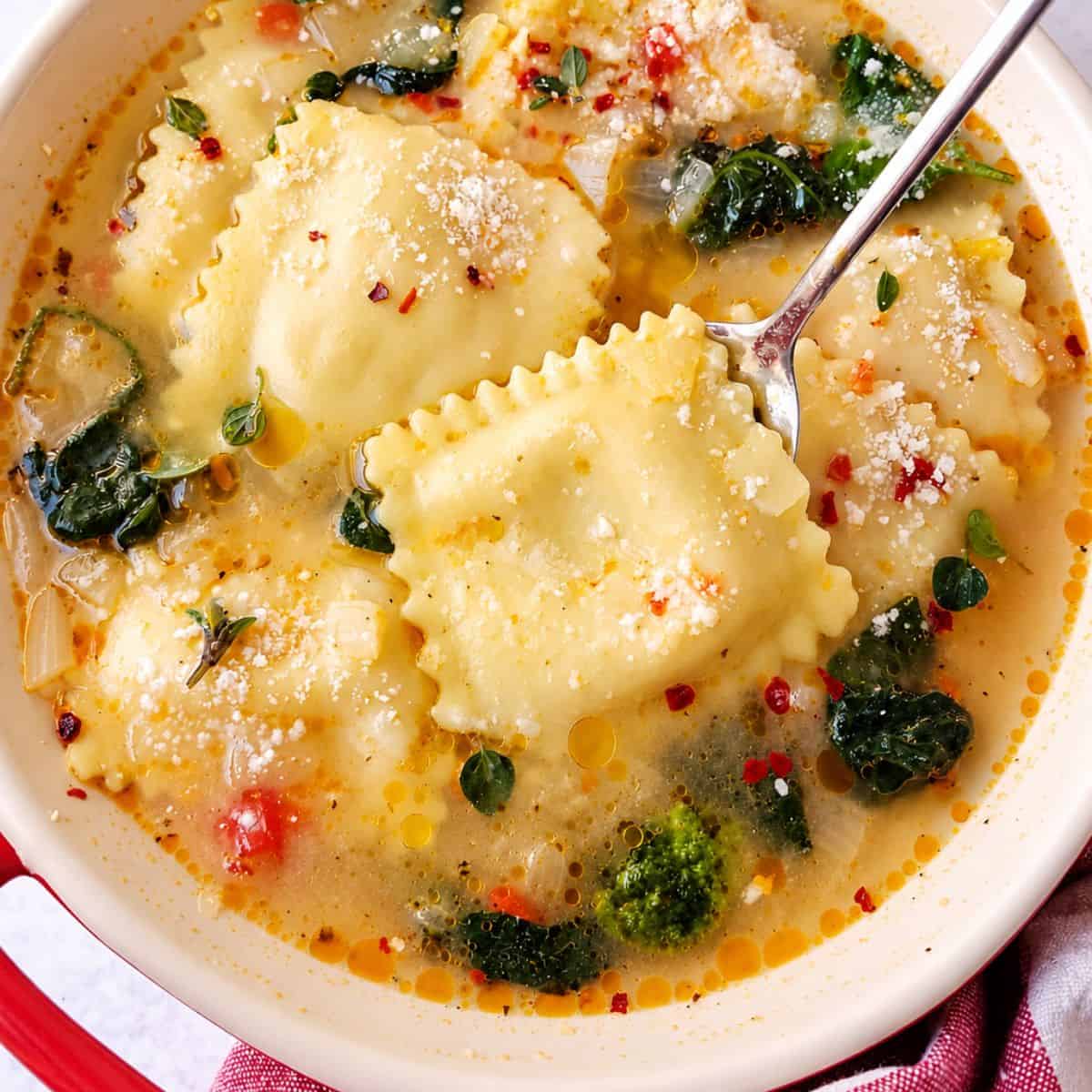 Filled pasta topped with Parmesan in a light broth with leafy greens and herbs.