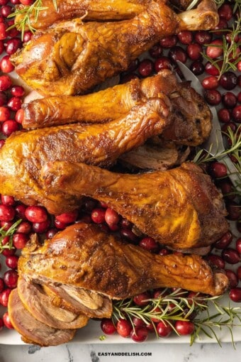 smoked turkey legs with cranberries and rosemary sprigs.