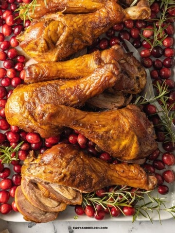 smoked turkey legs with cranberries and rosemary sprigs.