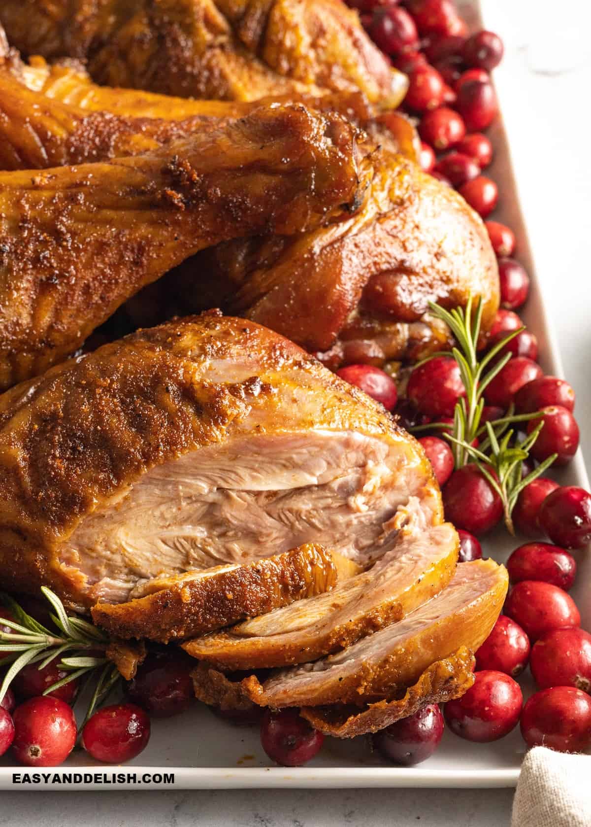 close up fo whole and sliced smoked turkey drumsticks ina party platter