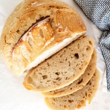 basic sourdough bread part whole and part sliced over parchment paper.