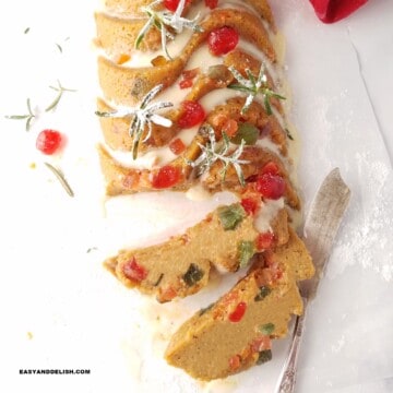 gluten-free fruit cake decorated for Christmas and partially sliced over parchment paper.