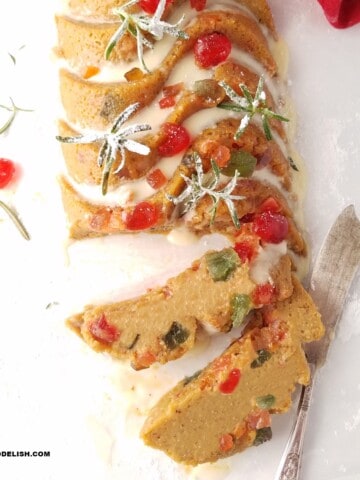 gluten-free fruit cake decorated for Christmas and partially sliced over parchment paper.