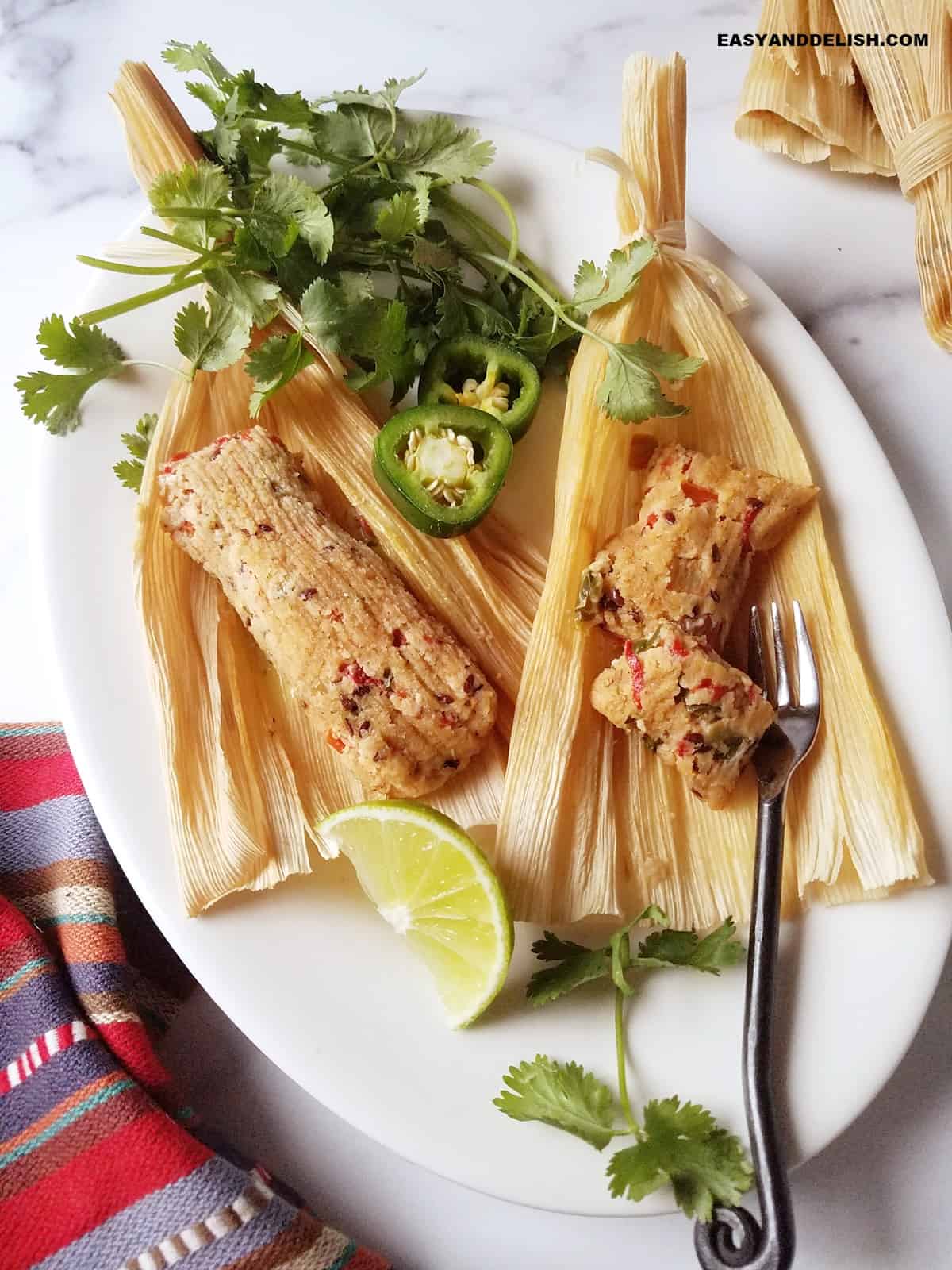 vegan keto tamales wrapped on a platter with lime wedges.