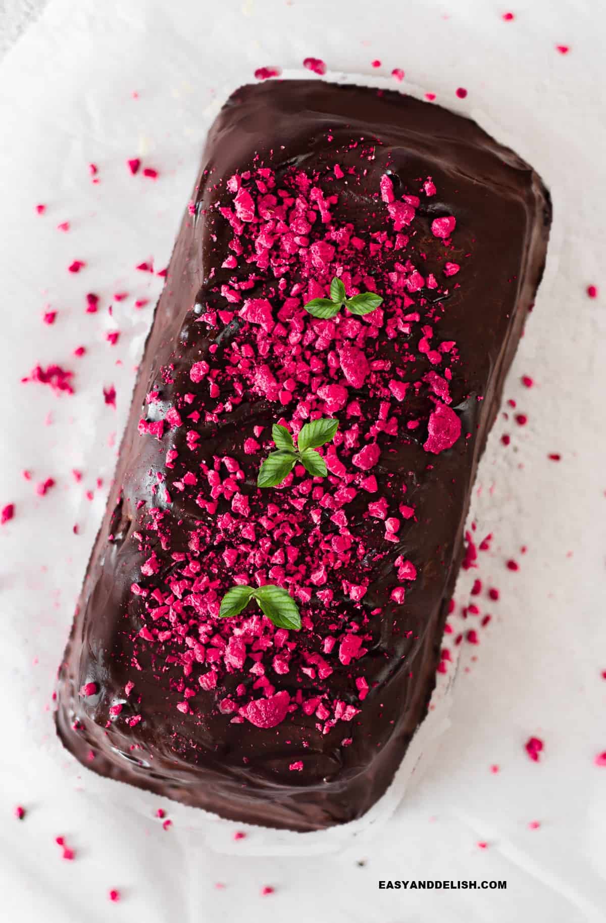 a whole no-bake chocolate biscuit cake garnished with berries and mint.