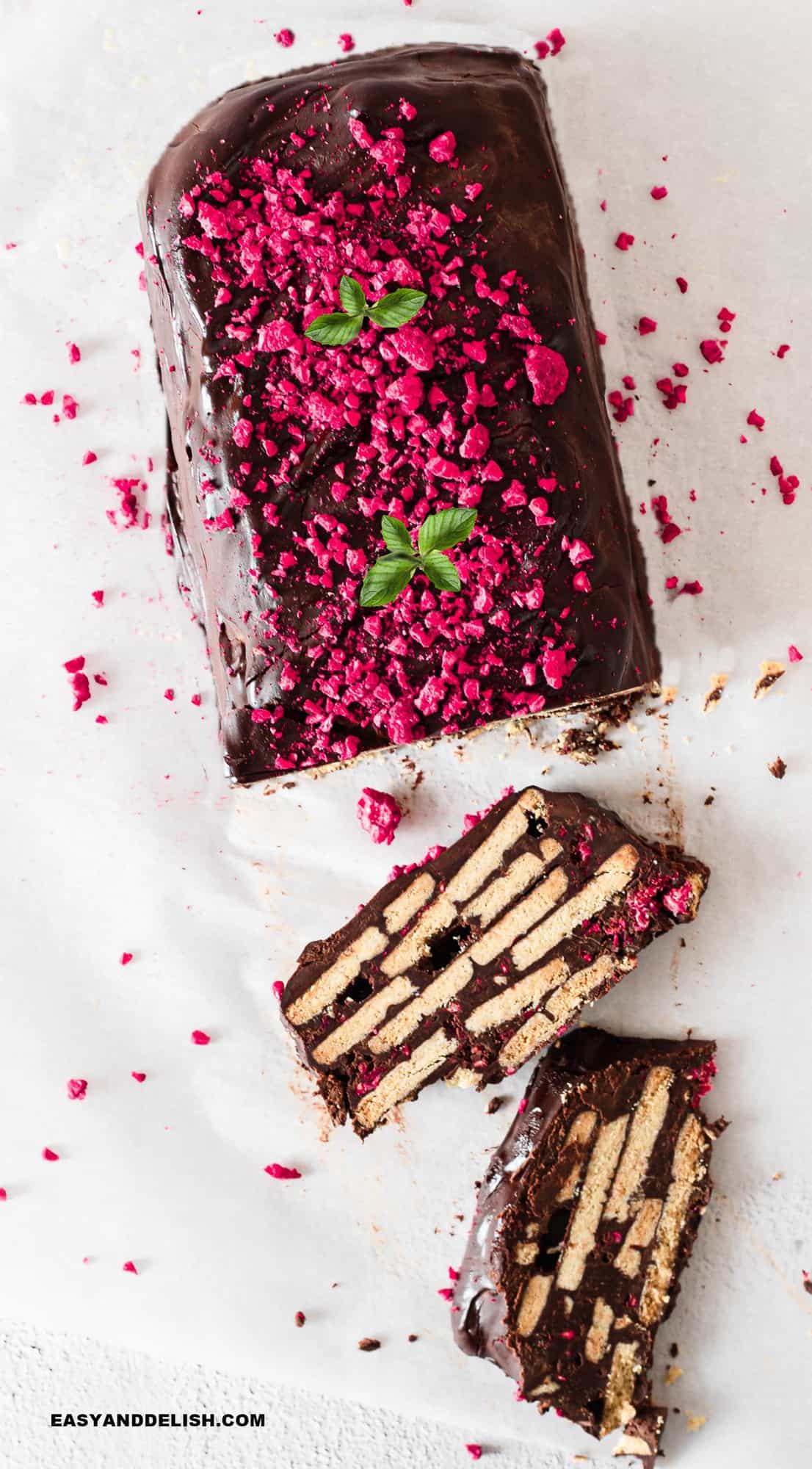 partially sliced biscuit cake topped with mint leaves and freeze-dried raspberries.