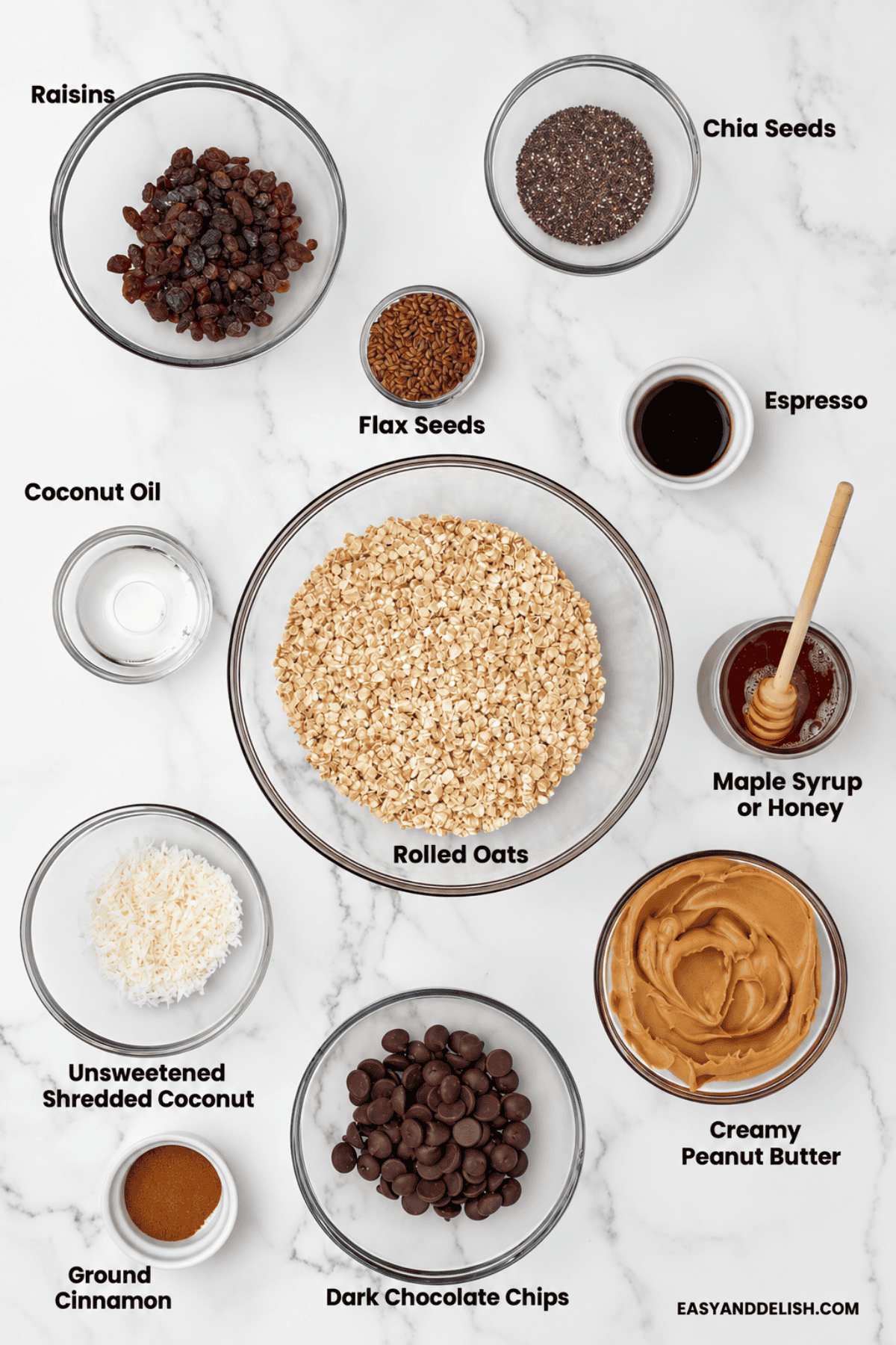 Bowls of homemade energy bar ingredients on a marble countertop.