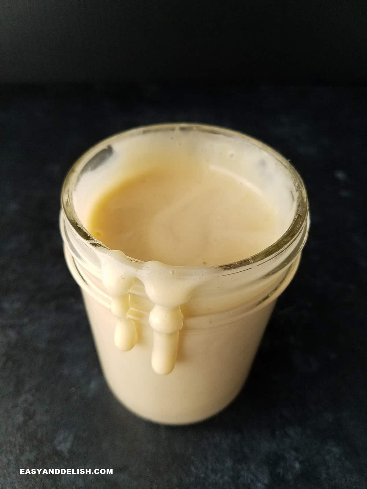uma jarra de leite condensado sem açúcar pingando nas laterais da jarra.
