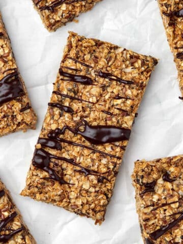 Homemade energy bars drizzled with chocolate on parchment paper.