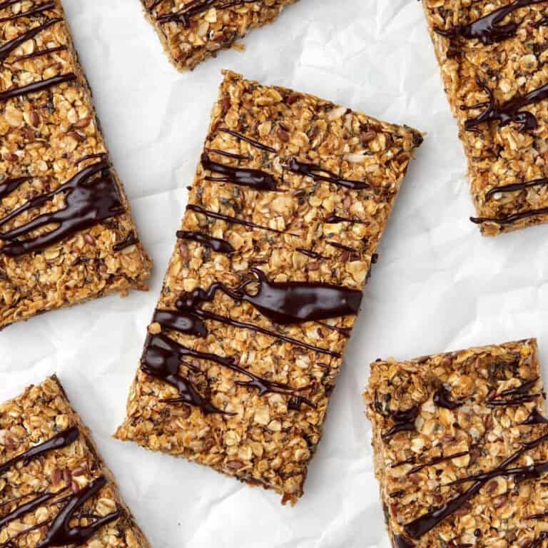 Homemade energy bars drizzled with chocolate on parchment paper.