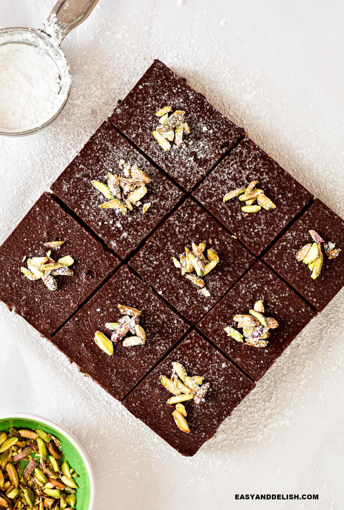 nine slice of no bake brownies over a table with garnishes around them.