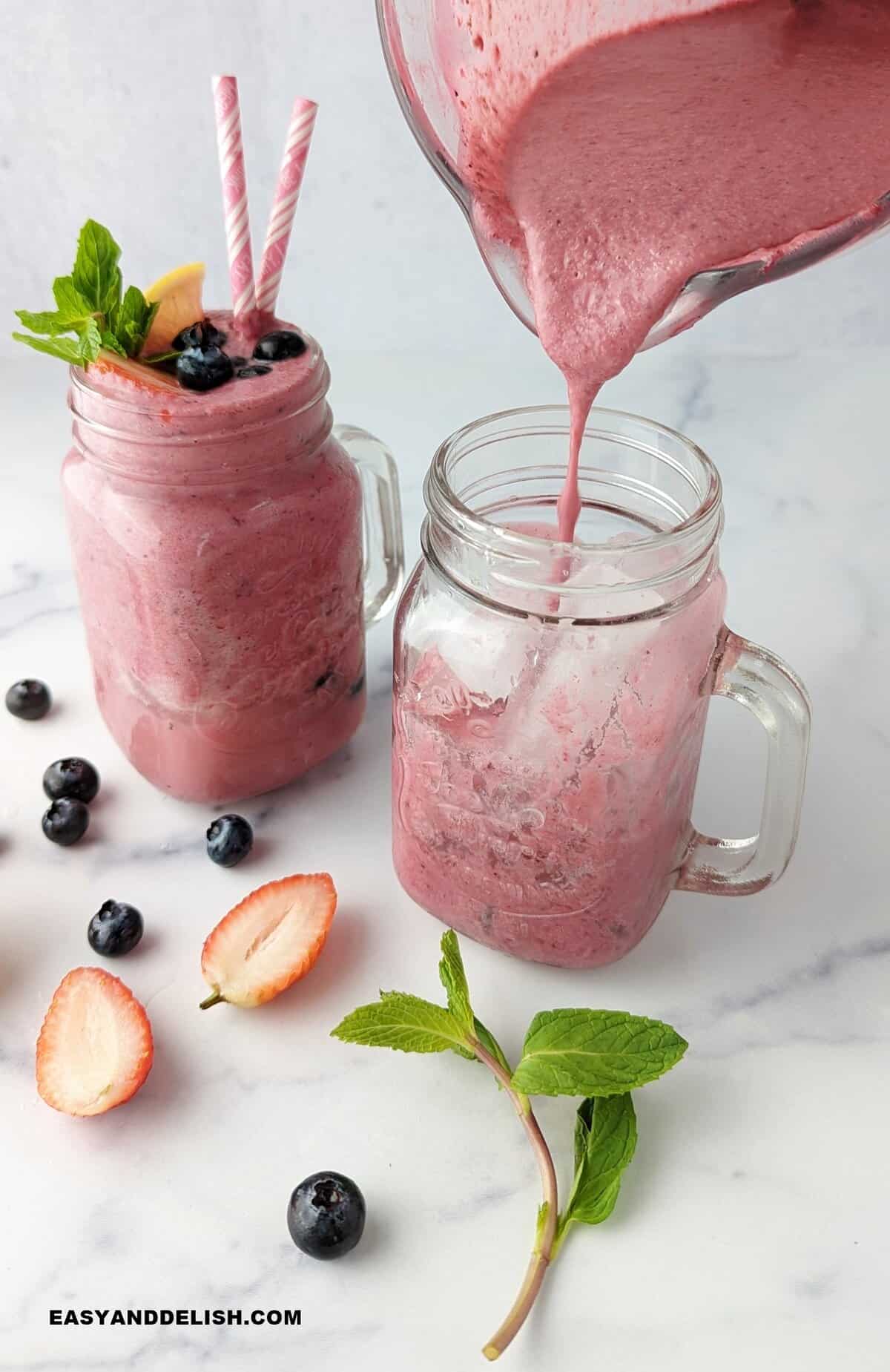 a blender pouring a creamy drink into a glass wioth ice plus garnishes around it.