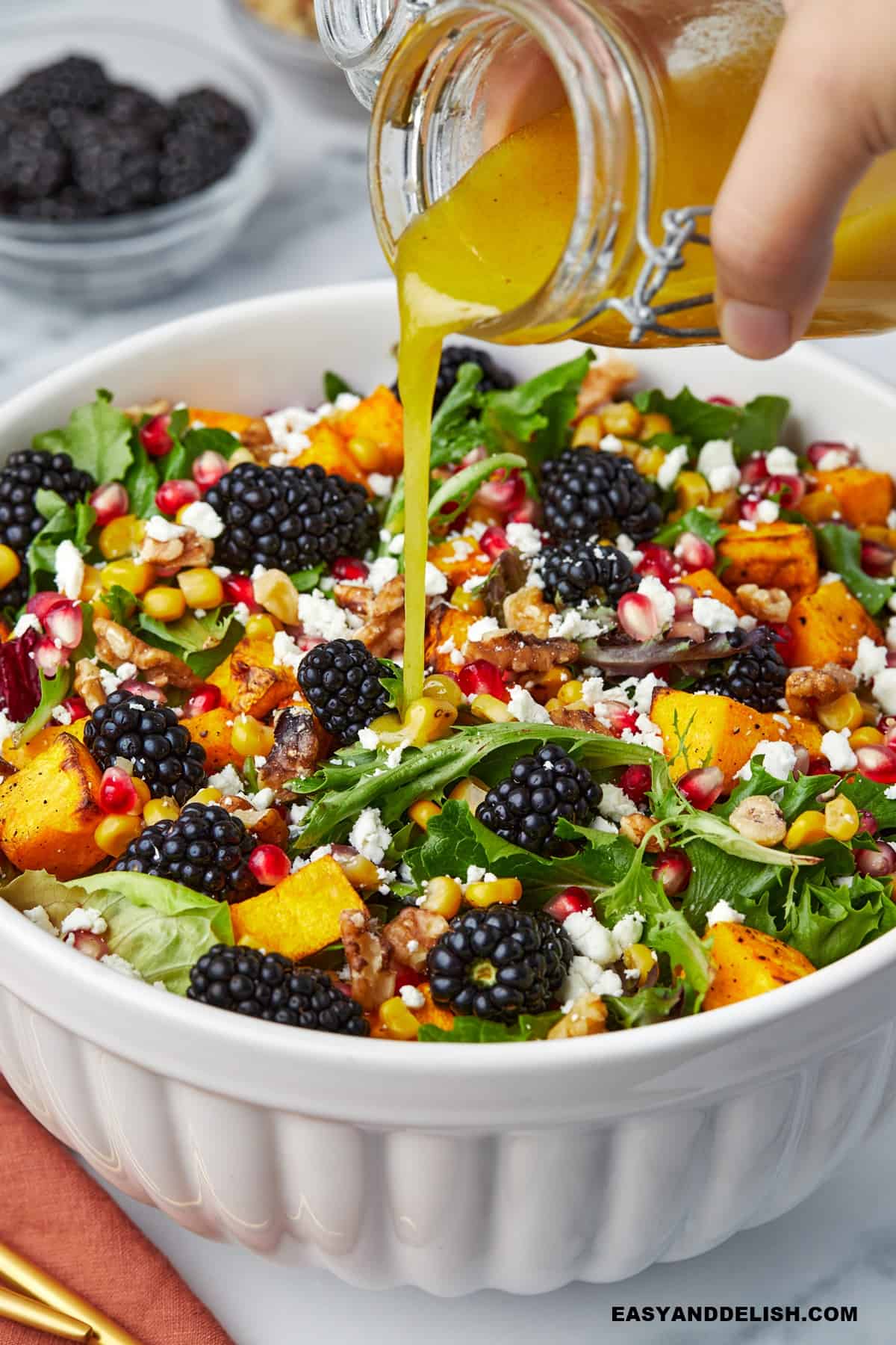 a jar pouring apple cider dressing on a salad.