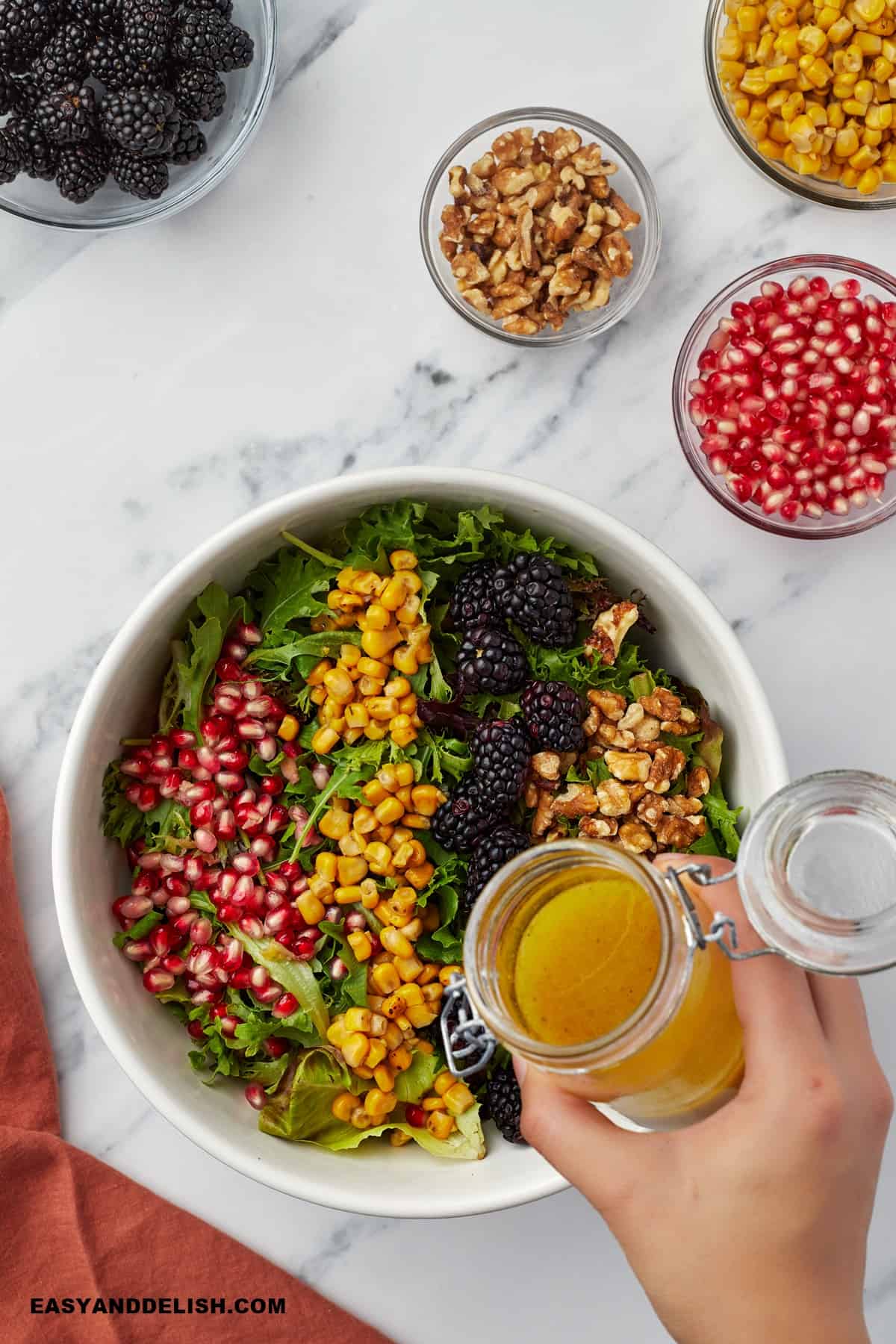 a jar of salad dressing over a bpwl of salad.