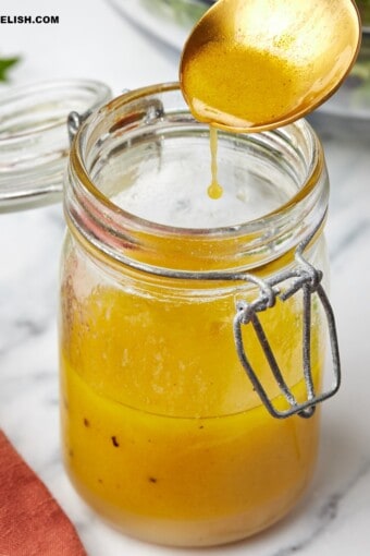 A spoon over a jar with apple cider vinaigrette .