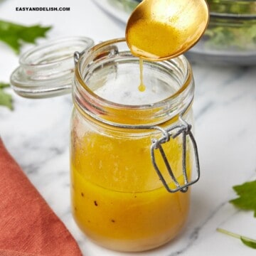 A spoon over a jar with apple cider vinaigrette .